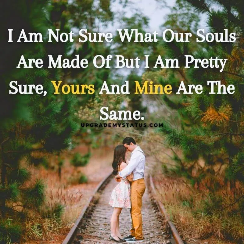 a couple is hugging on a rail road passing through trees over it love status quote is written